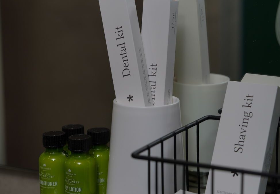 Close up of hotel toiletries including dental and shaving kits on countertop.