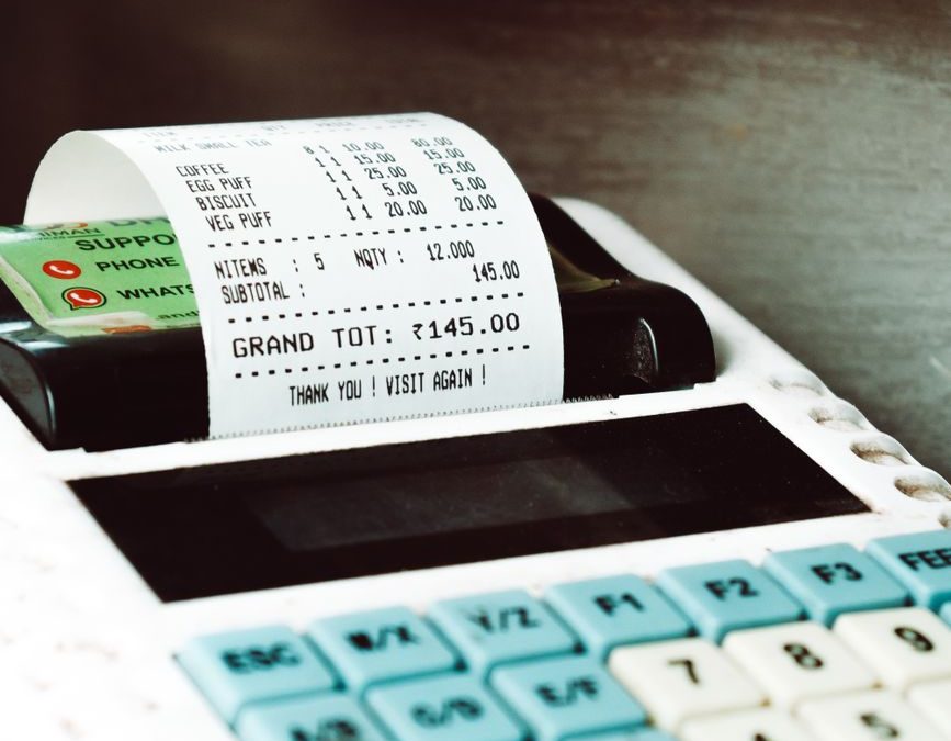 Close up shot of a cash register printing a receipt with a card nearby, in a retail store.