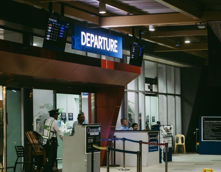 Night view of an airport departure gate with staff and passengers in a modern terminal.