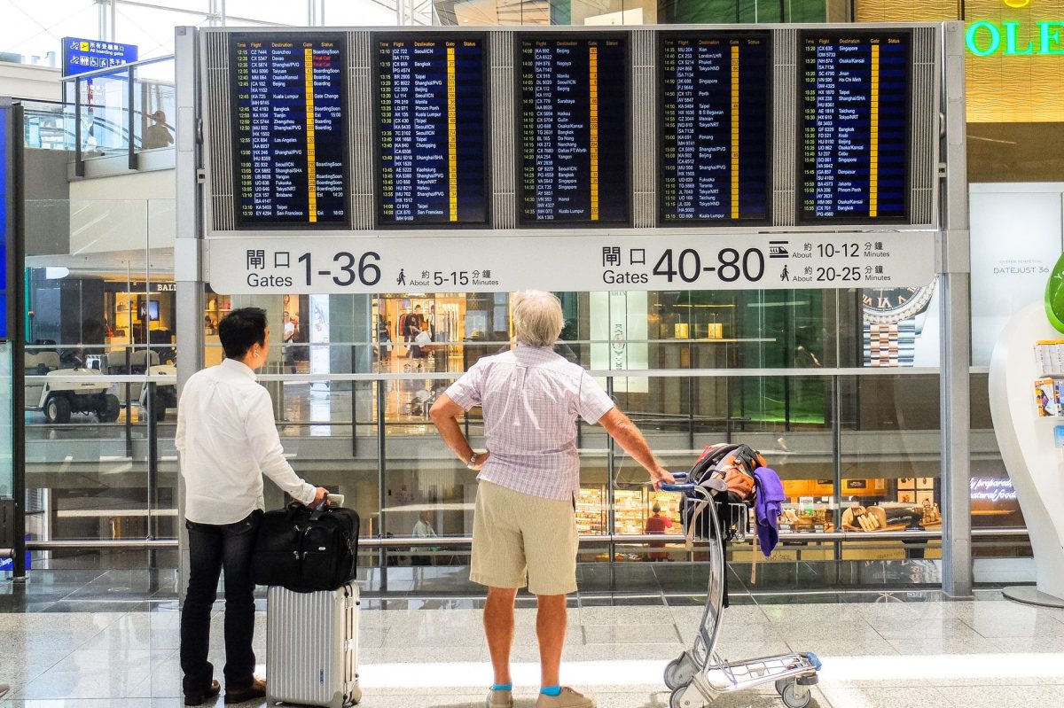 5 Bag-Drop Slipups That Can Derail a Travel Morning 1 Passengers review flight information on a digital board in Hong Kong airport terminal.