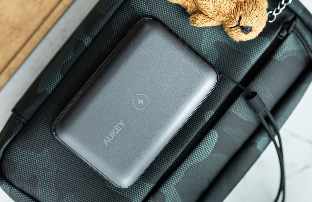 5 Bag-Drop Slipups That Can Derail a Travel Morning 4 Close up of a camouflage bag with a power bank and teddy bear keychain charm.