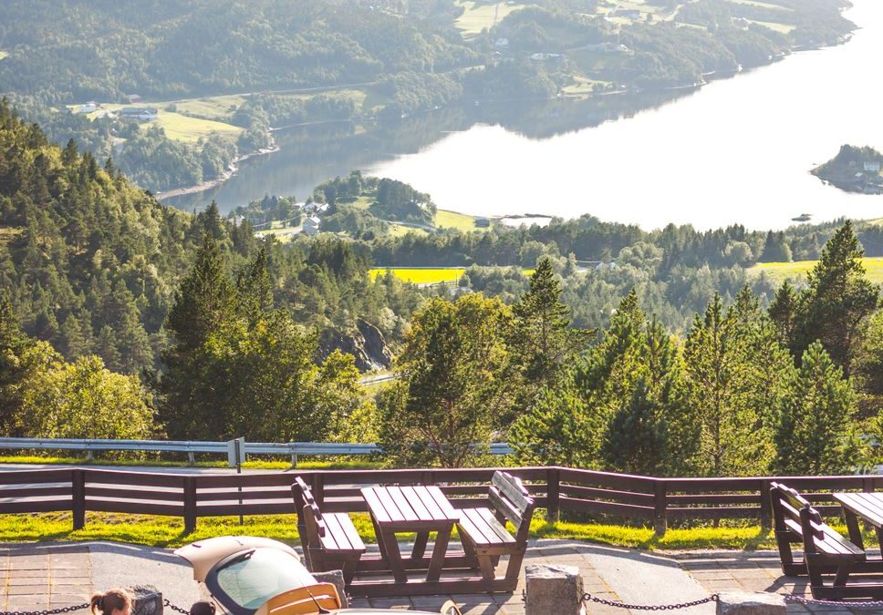 Breathtaking view of Norway&amp;amp;#39;s mountains with travelers and a car at a roadside stop.