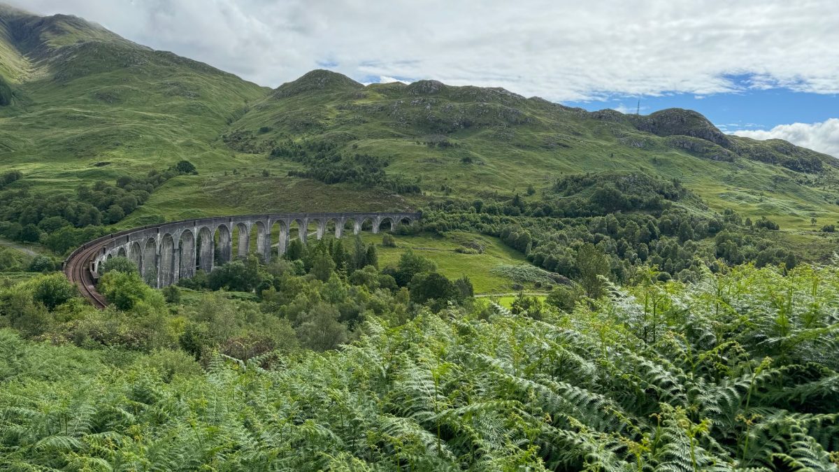 Captivating view of the iconic Glenfinnan Viaduct amid lush greenery in Scotland.