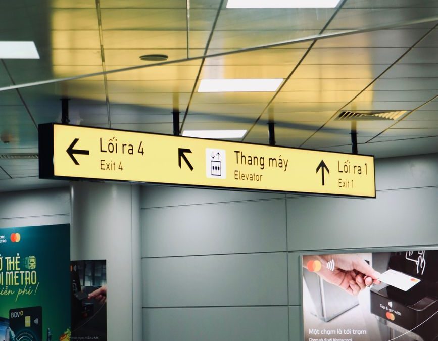 5 Airport Signs Travelers Misread Right When Time Gets Tight 1 Indoor view of directional signs for exits and elevator in a Vietnamese airport.