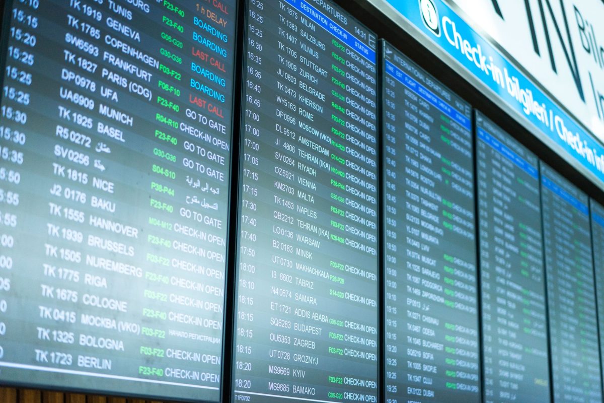 5 Airport Signs Travelers Misread Right When Time Gets Tight 2 Digital screens display flight information and schedules at an airport terminal.