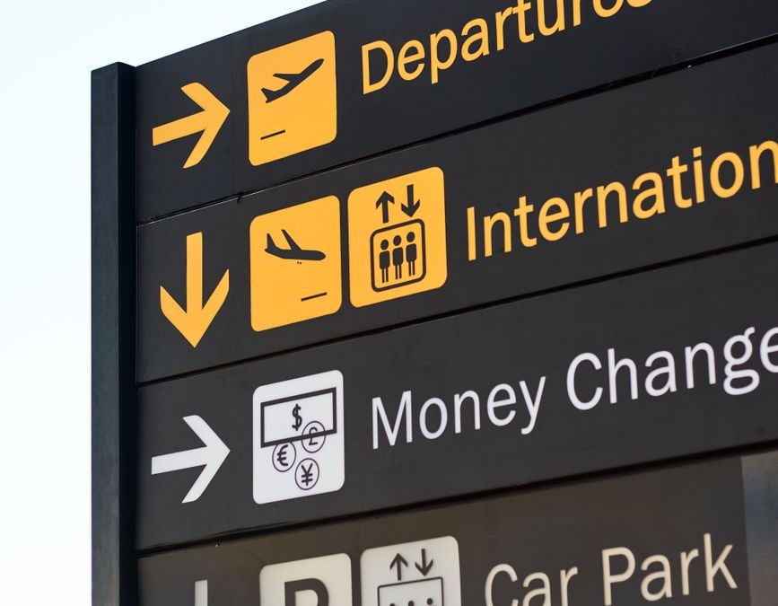 5 Airport Signs Travelers Misread Right When Time Gets Tight 5 Close up of airport direction signs for departures, international, money change, and car park.