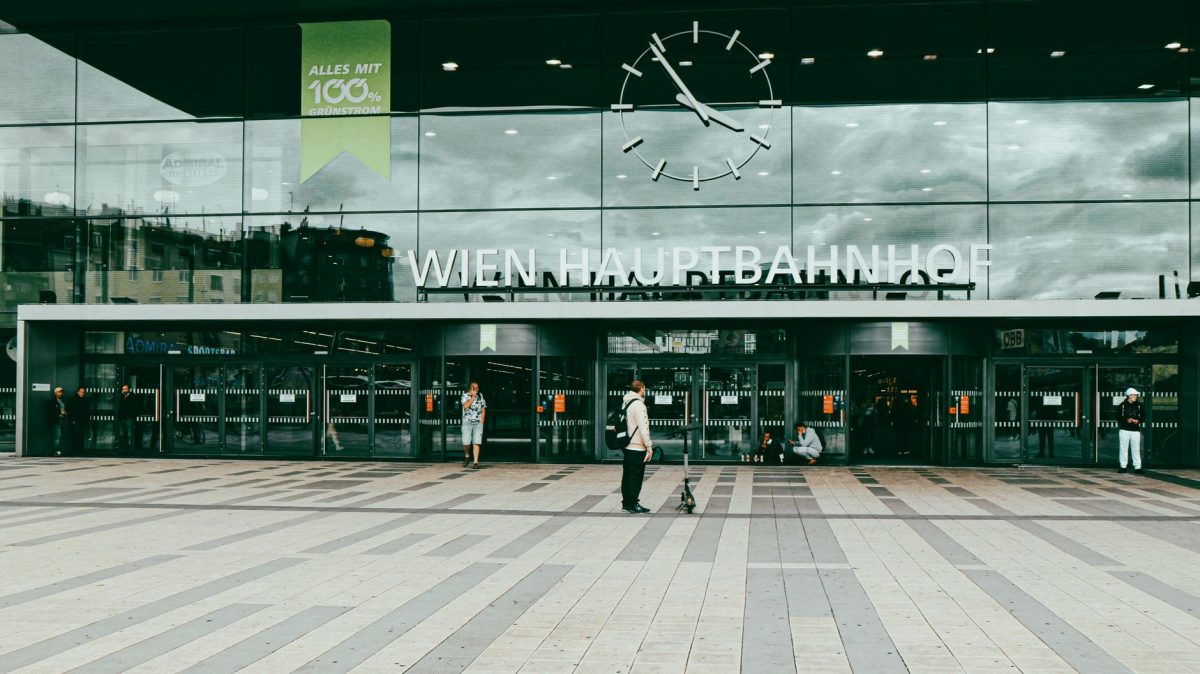 Entrance of Wien Hauptbahnhof with people and modern facade in Vienna, Austria.