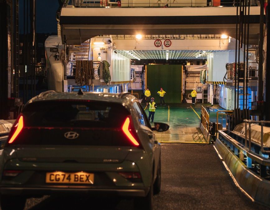 Nighttime scene of a car boarding a ferry in Scotland, highlighting travel and transportation.