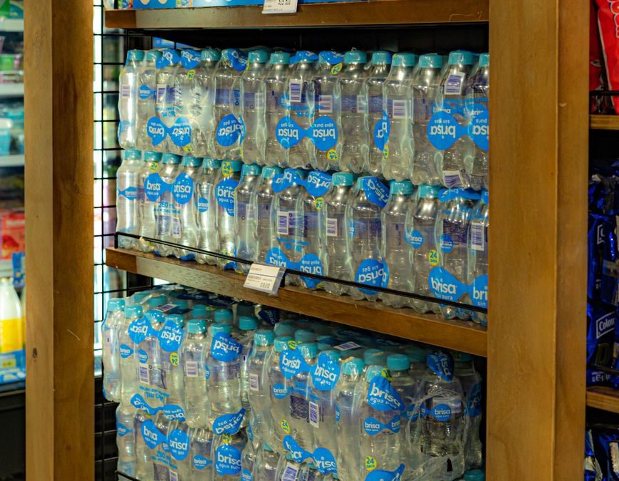 Bottled water neatly arranged on supermarket shelves displaying consumer goods.