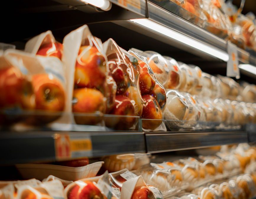 Packaged fresh apples displayed on a supermarket shelf with bright lighting.