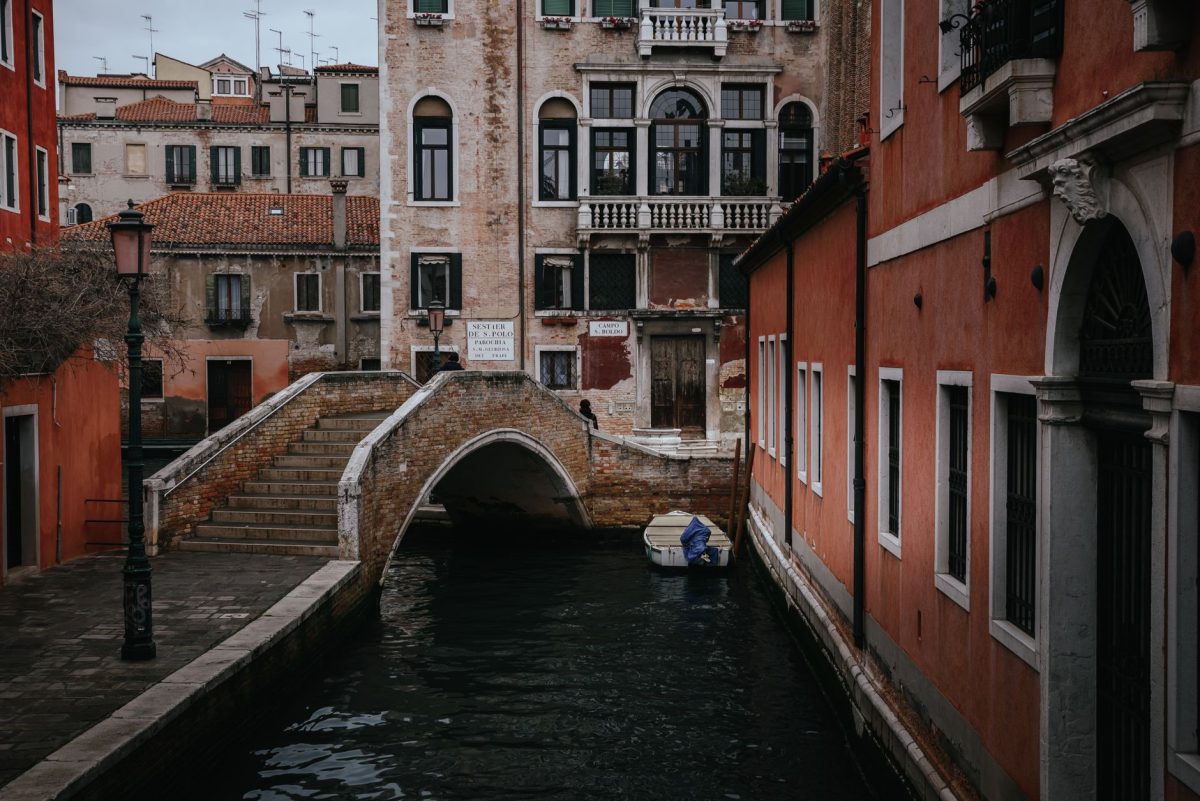 A serene view of a Venetian canal with classic architecture and a small boat under a bridge.
