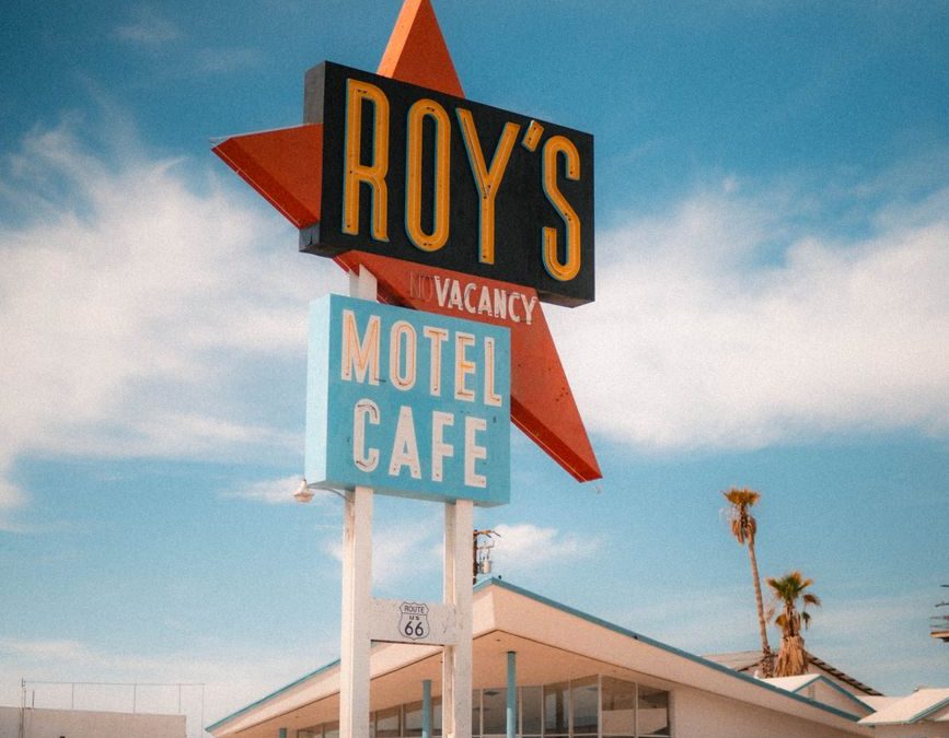 Vintage view of Roy&amp;amp;#39;s Motel and Café sign with classic car on Route 66.