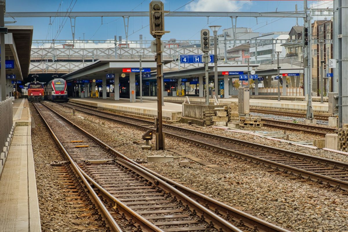 A vibrant urban train station with multiple platforms and trains arriving.