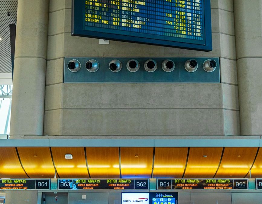 5 Airport Signs Travelers Keep Missing and Regret Later 2 Digital departure board and airline check in counters inside a modern airport terminal.