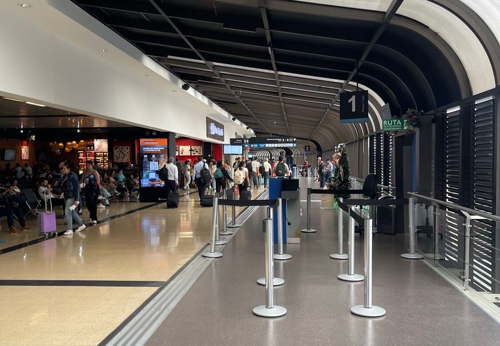 A busy airport terminal featuring shops and travelers waiting and walking.