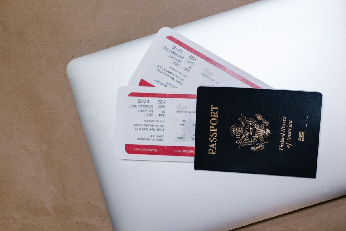 Close up of a passport and boarding passes on a laptop, symbolizing travel preparation.