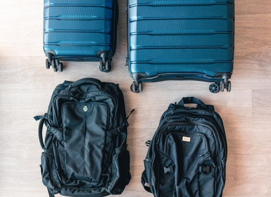Aerial view of modern luggage and backpacks arranged on a wooden floor.