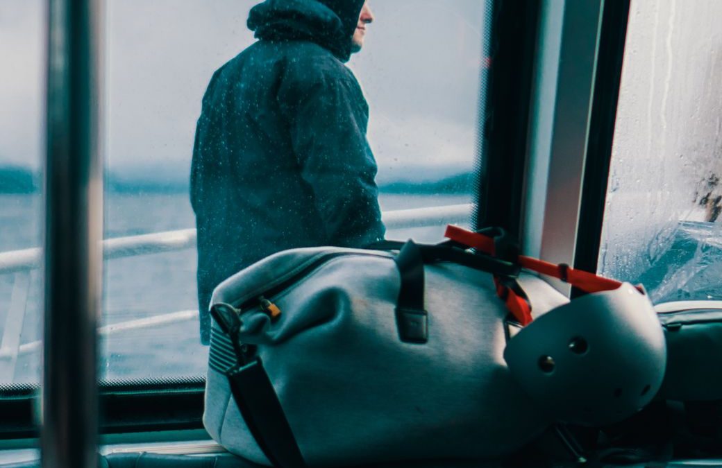 5 Ferry Boarding Habits That Keep a Short Crossing From Feeling Like a Fire Drill 3 Caught in a contemplative moment, a hooded man gazes at the ocean from inside a ferry.