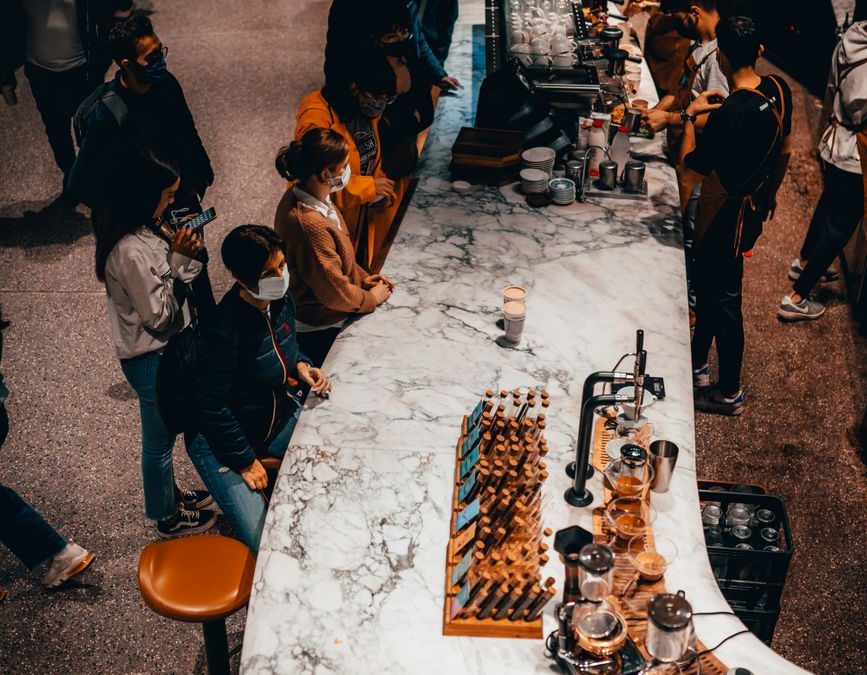 High angle view of people in a bustling coffee shop with a focus on a marble bar and chess set.