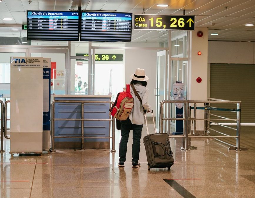 Woman with luggage exploring airport terminal. Solo travel and future adventures.