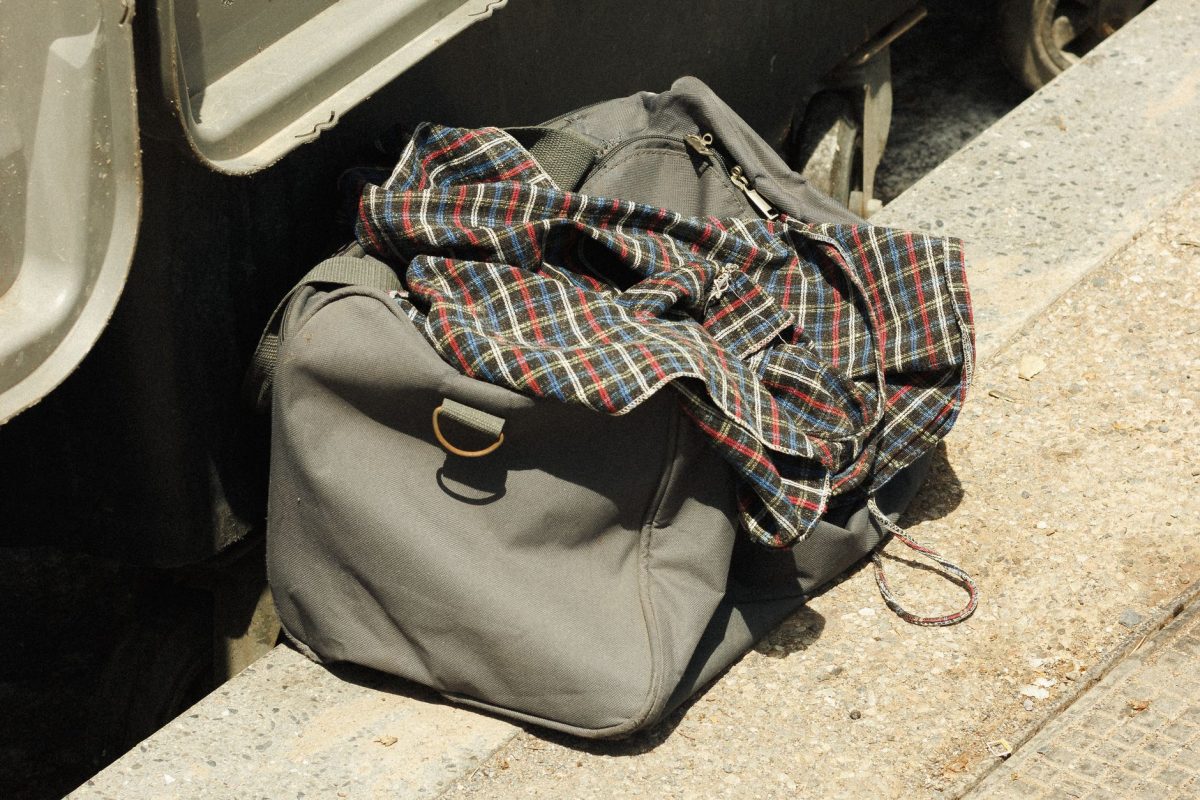 5 Train Station Mistakes That Make Trips Go Sideways Fast 5 Close up of a grey travel bag with a plaid shirt, placed near train tracks in daylight.