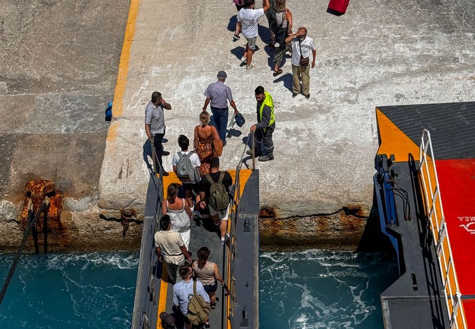 Passengers boarding a ferry at a bustling dock in Tinos, Greece.