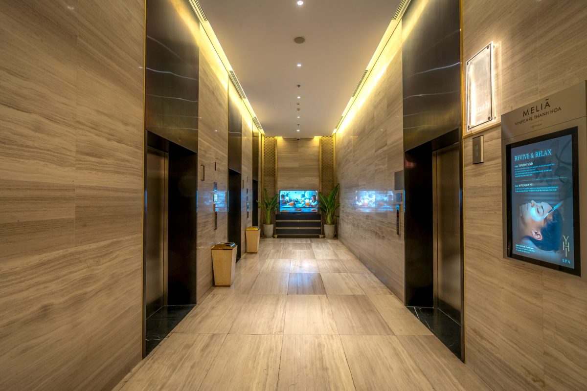 Elegant hotel corridor featuring marble floors and ambient lighting, exuding luxury.
