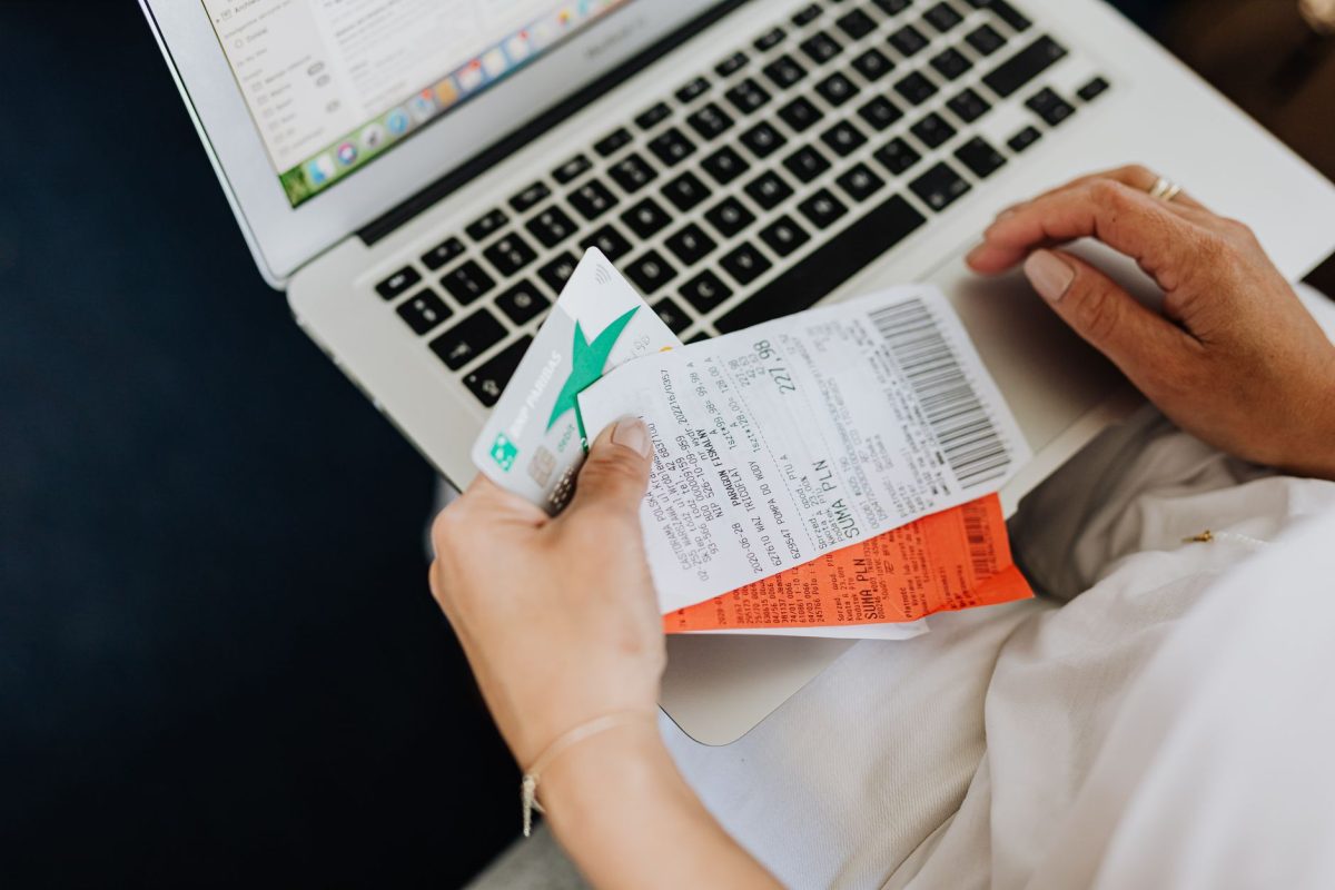 Close up of hands holding receipts and a bank card in front of a laptop, representing online shopping and e commerce.