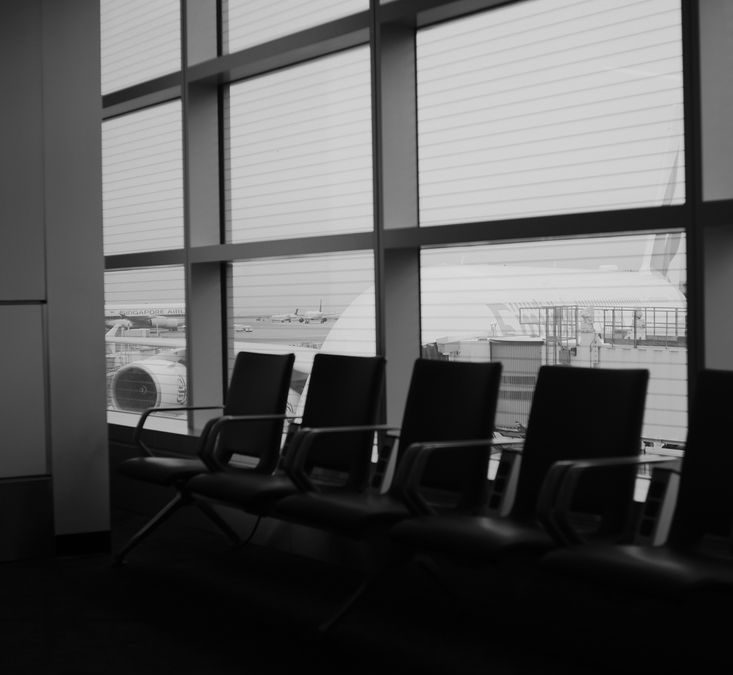 Empty chairs in a quiet airport terminal in grayscale with window view.