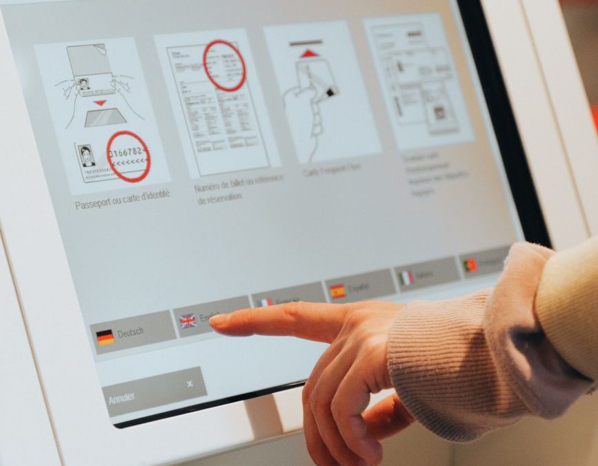 Hand interacting with airport self service kiosk for check in.