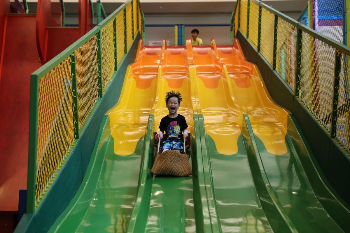 A cheerful child sliding down a colorful slide in an indoor playground, showcasing fun and excitement.